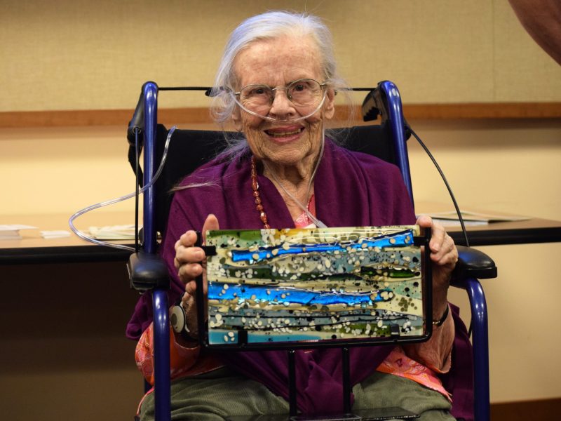 a woman smiles with a piece of art