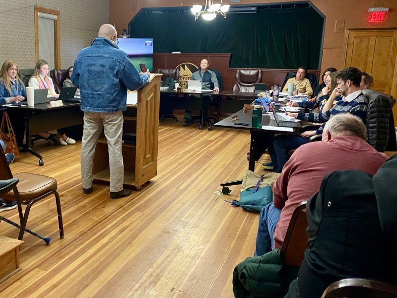 man standing at podium at town meeting
