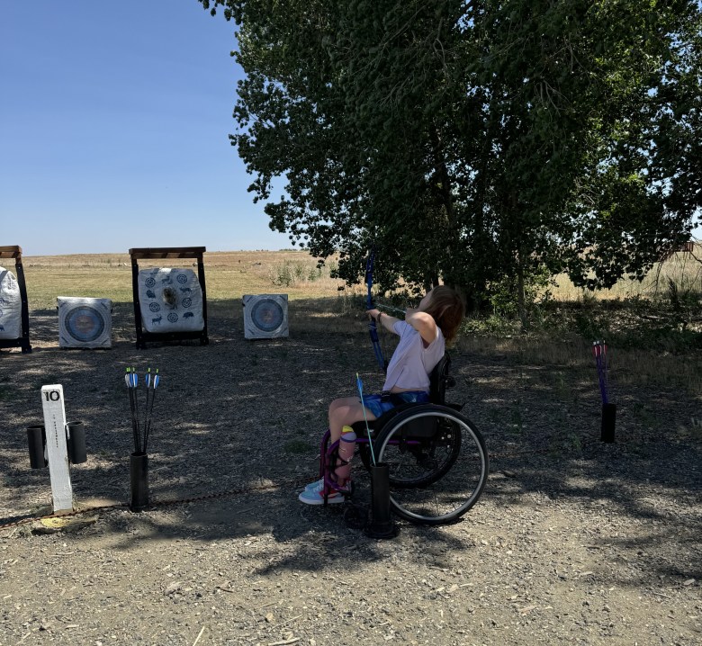 A girl shoots an arrow at an archery board.