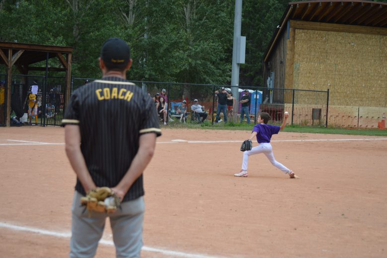 A coach for Gilpin County watches Clear Creek pitcher throw during a youth baseball game in Idaho Springs on June 28.
