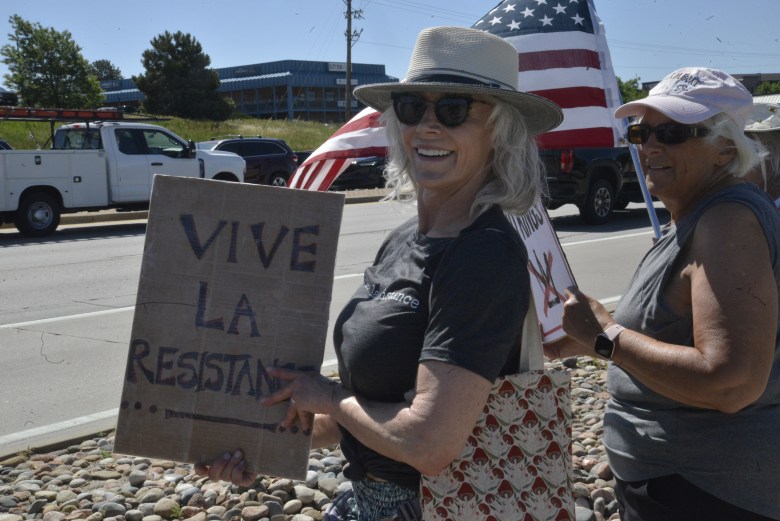 A woman stands with a sign at a protest.