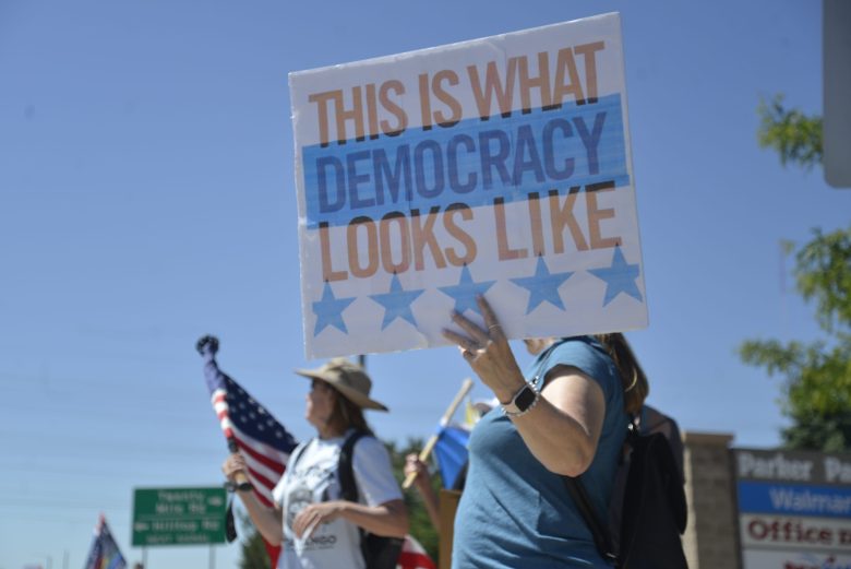 A woman holds a sign that says "This is what democracy looks like."