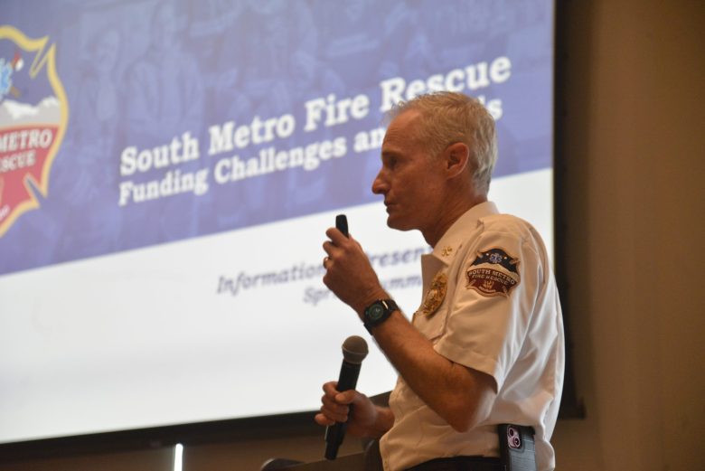 A fire chief stands with a microphone at a presentation