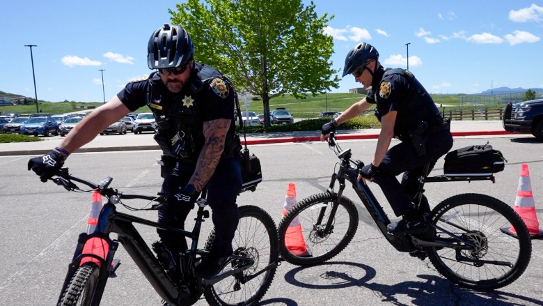 Two police officers ride bikes.