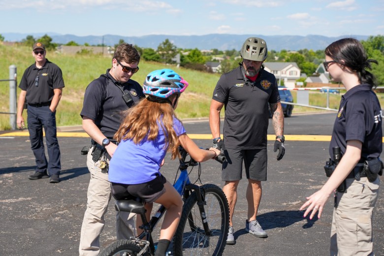 Police officers help a child ride a bike.