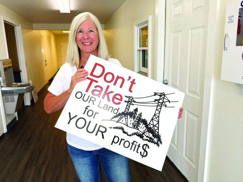 Elbert County Environmental Alliance board member Kerry Jiblits holds a protest sign at the county commissioners' public hearing on Xcel Energy's Colorado Power Pathway plan.