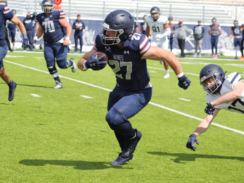 Running back Max Barnes evades a tackle by teammate Brock Zanetell
