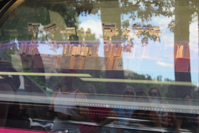 As seen in the reflection, people stand in line at the HipPOPs food truck to buy its handcrafted gelato bars during Golden's 4th of July Festival at Lions Park.