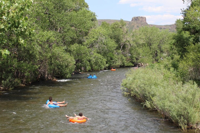 Looking east from the pedestrian bridge near U.S. Highway 6 on June 28, tubers float along Clear Creek with South Table Mountain's Castle Rock visible in the background.