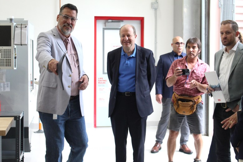 Director Sean Grubb, at left, gives Colorado Gov. Jared Polis, center, and other officials a quick tour of the new CoorsTek Academy Training Center during a July 16 ribbon-cutting ceremony.