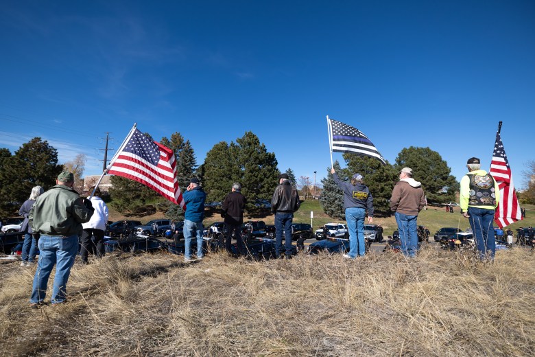 Community members line County Line Road and hold up flags for Golden Police Officer Evan Dunn's funeral procession on Nov. 13.