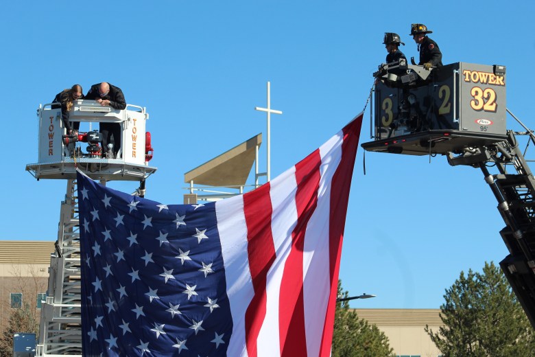 Firefighters from Golden, at left, and South Metro, at right, tie a giant American flag between their aerial ladder trucks Nov. 13 ahead of Golden Police Officer Evan Dunn's funeral procession.