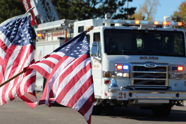 As supporters wave American flags, a Golden fire truck makes its way down County Line Road during Golden Police Officer Evan Dunn's funeral procession to Mission Hills Church.
