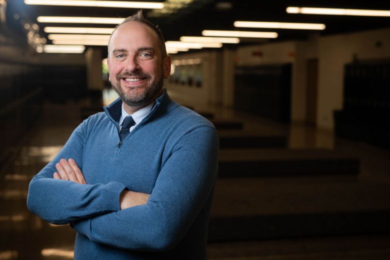 Justin Ralston, smiling with arms crossed, stands in a school hallway during his first week as Weld RE-8 superintendent.