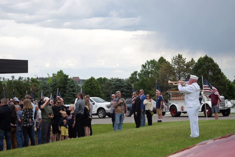 a man plays a bugle at a burial ceremony