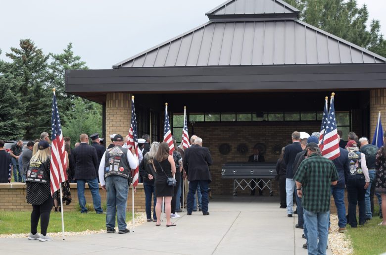 people hold flags at a burial ceremony