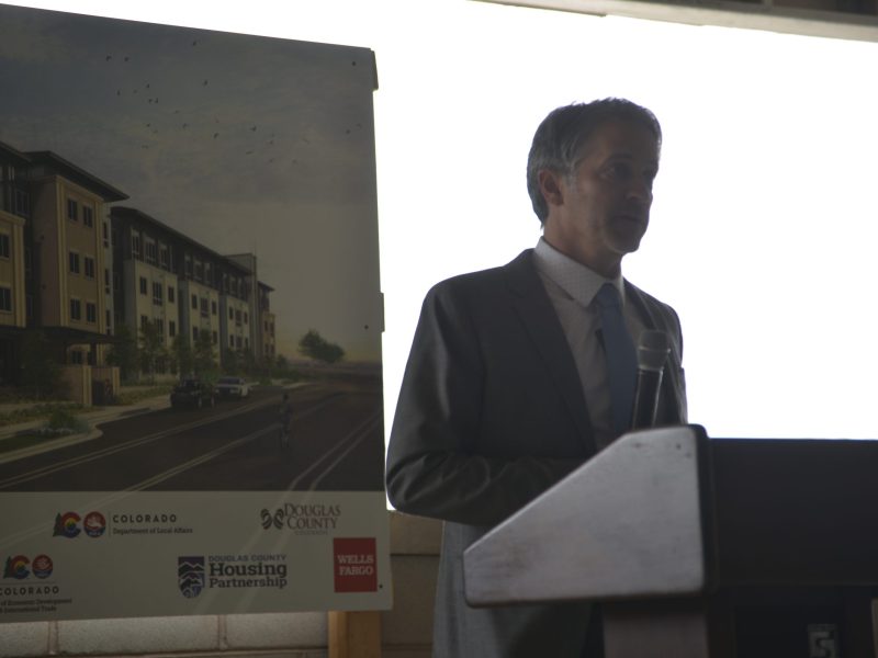A man speaks at a podium at a construction sight.