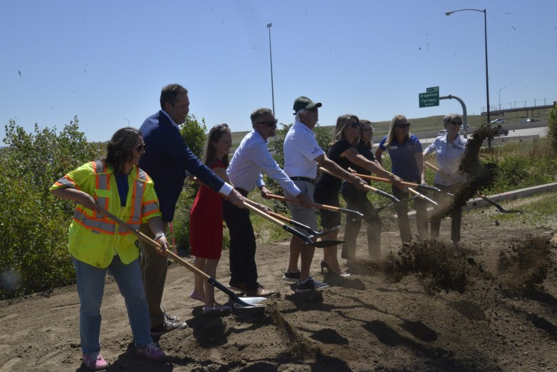 A group of people shovel dirt at a groundbreaking.