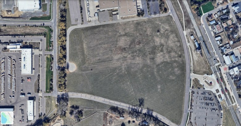 Aerial image from Google Earth showing a large undeveloped 13.5-acre field in Thornton, Colorado, bordered by roads and parking lots. RTD’s Eastlake/124th light rail station is visible in the lower right corner.
