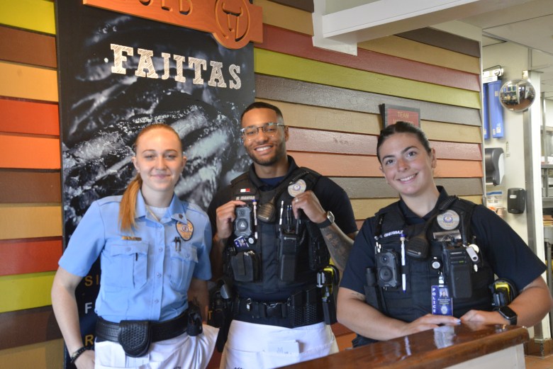 Three police officers stand together for a photo in a restaurant.