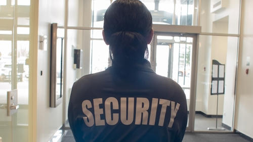 A school security guard stands in front of the front door