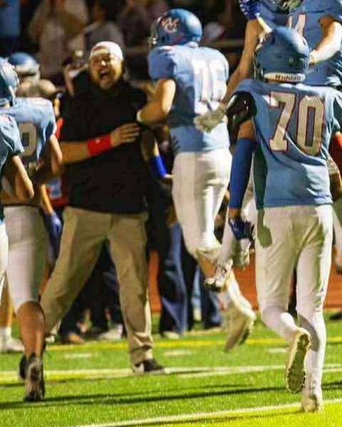 Weld Central's new head football coach, Travis Letkomiller (left) celebrates a play with other Rebels' players.